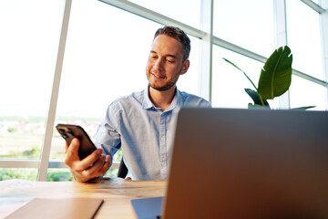 Portrait of young man sitting at his desk in the office and using computer