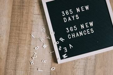 Letterboard with motivational quote 365 New Days, 365 New Chances with messy letter on wooden...