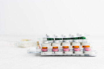 Pile of various pills and tablets in a blister pack on white background, healthcare and medicine concept
