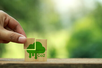 CO2 emission reduction concept.Hand holding wooden cubes with Co2 icon Ideas for decreasing CO2, carbon footprint and carbon credit to limit global warming.Renewable energy.carbon credit. - obrazy, fototapety, plakaty