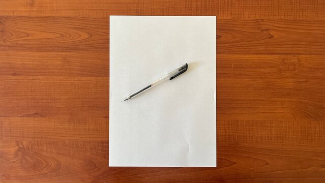  pen on white paper background lay on brown wooden background