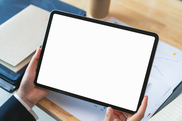 Businessman hand holding digital tablet with blank screen for graphic display montage on the desk in office.