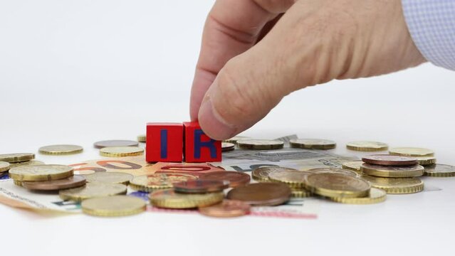 IRAP - A hand inserts letters on blocks one by one to form tax on top of us euro money. Regional Tax on Productive Activities.