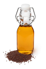 Bottle with brown mustard oil and black mustard seeds in front isolated on white background close up