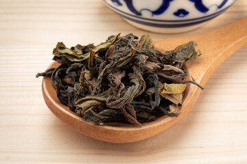 Fototapeta na wymiar Choui Fong dried tea leaves close up on a wooden spoon