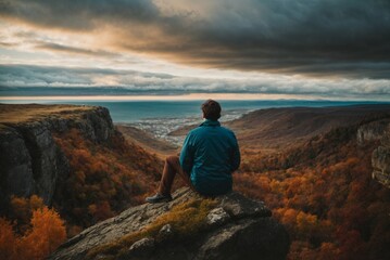Naklejka na ściany i meble Back view of a man sitting alone at the big mountains.