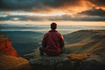 Back view of a man sitting alone at the big mountains.