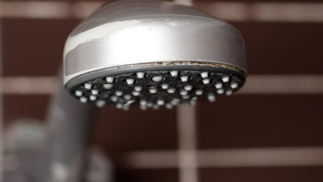 Close up of turning off running water from old shower head in bathroom to save natural resources