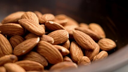 Dried dieting almonds nuts in dark wooden bowl close up. Rotation