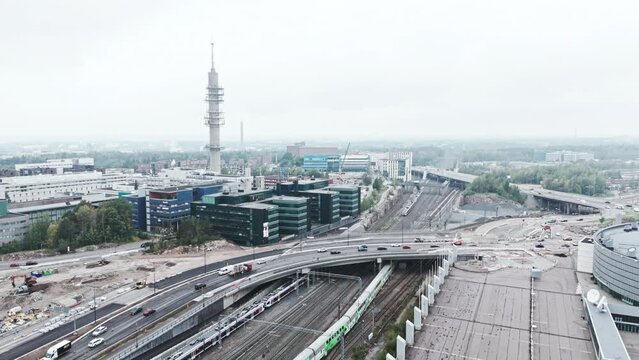 Wide aerial shot approaching a bleak industrial concrete television and radio link tower in Pasila, Helsinki, Finland on a bright and foggy day. Train railway in foreground.