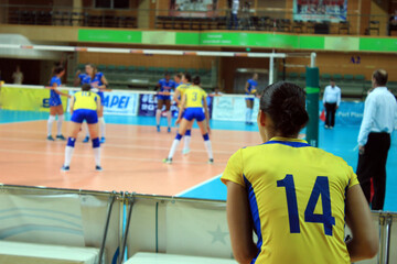 A volleyball player watches the play of her teammates during a volleyball match.