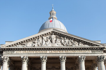 Fototapeta na wymiar Cúpula del Panteón de París con la bandera francesa ondeando al viento y la fachada con esculturas en piedra en bajorelieve, francia