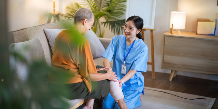 Physical therapist caregiver Asian and Caucasian senior women trust moving hand in rehabilitation. Physiotherapy healthcare, Medical caregiver consulting disabled elderly patient at home