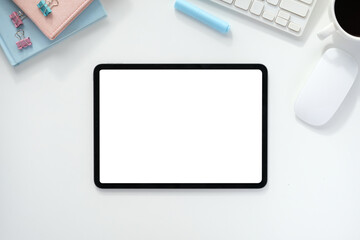 The top view image of white workspace is surrounding by a white blank screen tablet and various equipment.