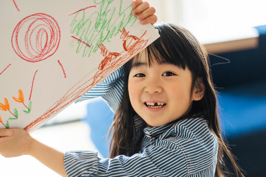描いた絵を掲げる日本人の女の子