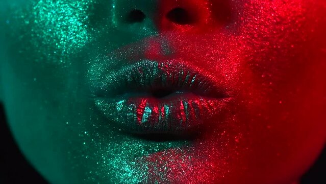 Fashion model woman kiss lips in bright sparkles, colorful neon lights, beautiful sexy girl lips, mouth. Trendy glowing gold skin make-up. Art design makeup. Glitter metallic shine makeup