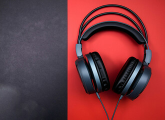 Black headphones on red and black background, top view, copy space for text.