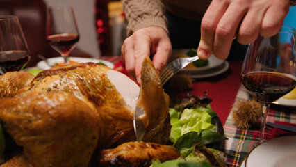 Man cutting roasted Chicken with knife for thanksgiving day in home