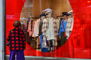 female mannequins appear to peer at passers-by from the window of a clothing store