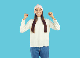 Cheerful positive young woman standing with her fists raised. Excited enthusiastic girl in white...