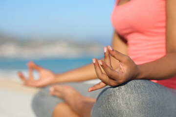 Black yogi hands doing yoga in the beach
