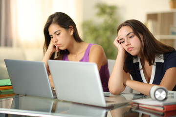 Two bored students waiting online content at home - obrazy, fototapety, plakaty