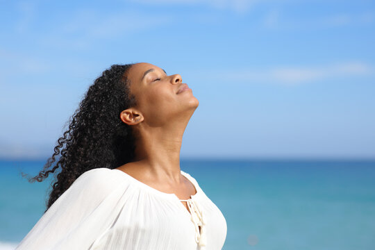 Black woman in white breathing in the beach
