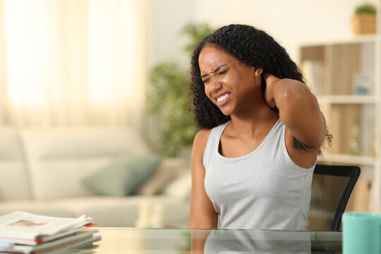 Black woman suffering neck ache sitting at home