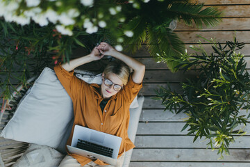Top view of woman working outdoors in the garden, with laptop on legs. Businesswoman working...