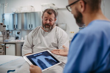 Doctor showing overweight patient chest x-ray, discussing test result in emergency room....