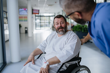 Supportive nurse soothing a worried patient in wheelchair. Illnesses and diseases in middle-aged men's health. Compassionate physician talking with stressed patient. Concept of health risks of