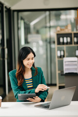 Young beautiful Business woman typing on tablet and laptop while sitting at the working white table office..