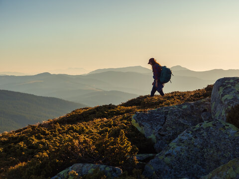 Descent of hiker tourist woman with backpack during mountain trekking from the top.