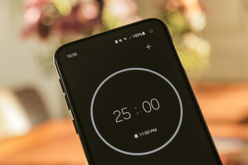 A phone with a black and white 25-minute timer to study with the pomodoro method on a blurry background