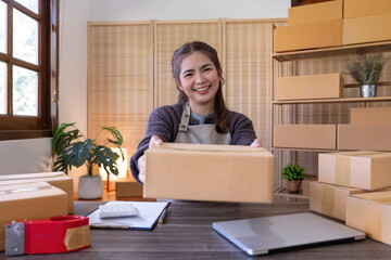 Young woman working online ecommerce shopping at her shop. Young woman seller prepare parcel box of product for deliver to customer. Online selling, ecommerce. Selling products online