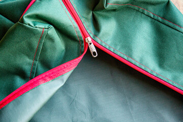 Close-up of a red zipper on a green fabric with red stripes