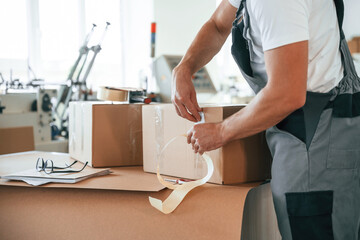 Process of packaging the product. Handsome man is working at the factory of creating eco boxes