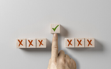 right choice concept. businessman hand selects wooden cube with green tick against background of...