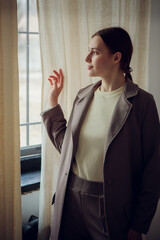 Fototapeta premium A young girl in strict men's clothes near the window