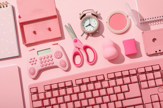 Stationery, cosmetics, alarm clock and keyboard on pink background, top view