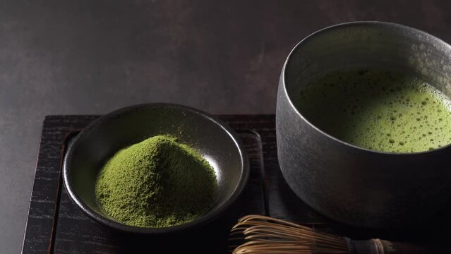 Matcha and matcha powder set against a dark background. Chasen (tea whisk). Close-up.