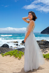 Teen girl in dress by lava shore of Hawaiian ocean
