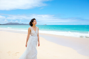 Fototapeta na wymiar Teen girl in white dress walking on hawaiian beach