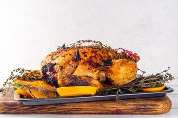 Christmas and Thanksgiving traditional baked chicken. Whole roasted chicken for holiday dinner, with oranges and thyme, on Christmas or Thanksgiving decorated table