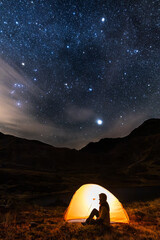 Woman in tent at night watching starry sky, adventure, wild tent