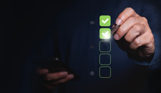 Businessman uses pen to mark correct place in checklist to guarantee quality control ISO concept Quality certification