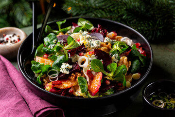Close up of Christmas winter salad with beetroot, oranges, walnuts, pomegranate, dried cranberries,...
