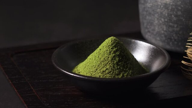 Matcha and matcha powder set against a dark background. Chasen (tea whisk). Close-up.