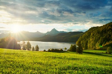 Beautiful Bavarian landscape with a meadow, mountains and a lake, sunrise, partly cloudy