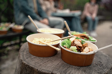 Bowls of food on wooden surface in nature - People enjoying Asian food in nature